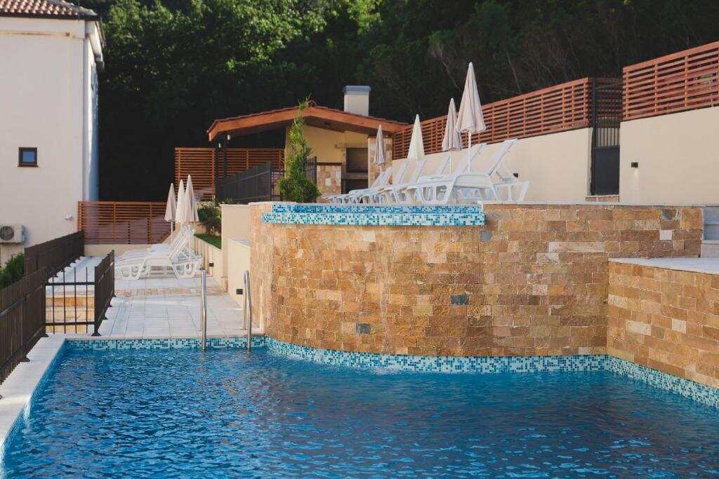 Outdoor pool with stone wall and sun terrace at Villas Promis